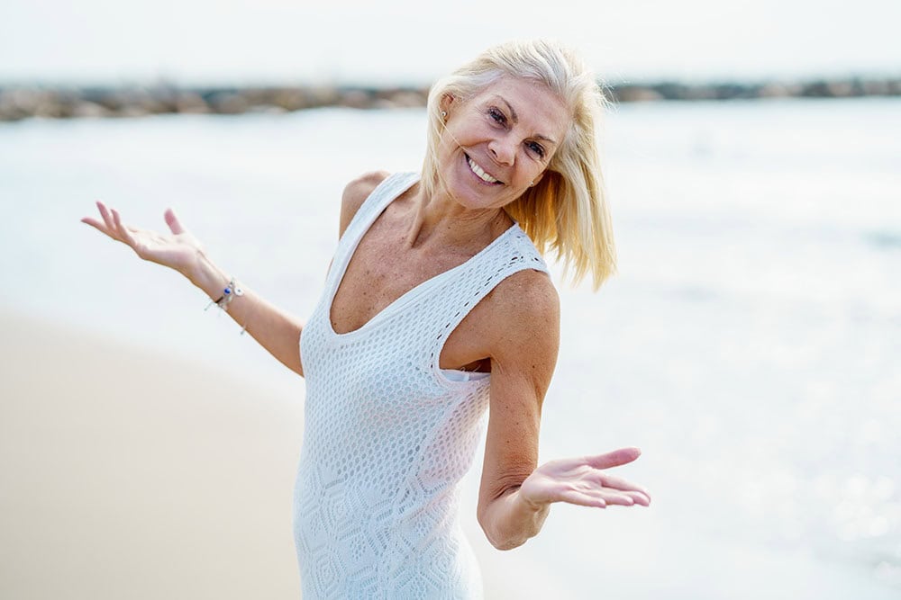 Smiling older woman enjoying a walk along the water